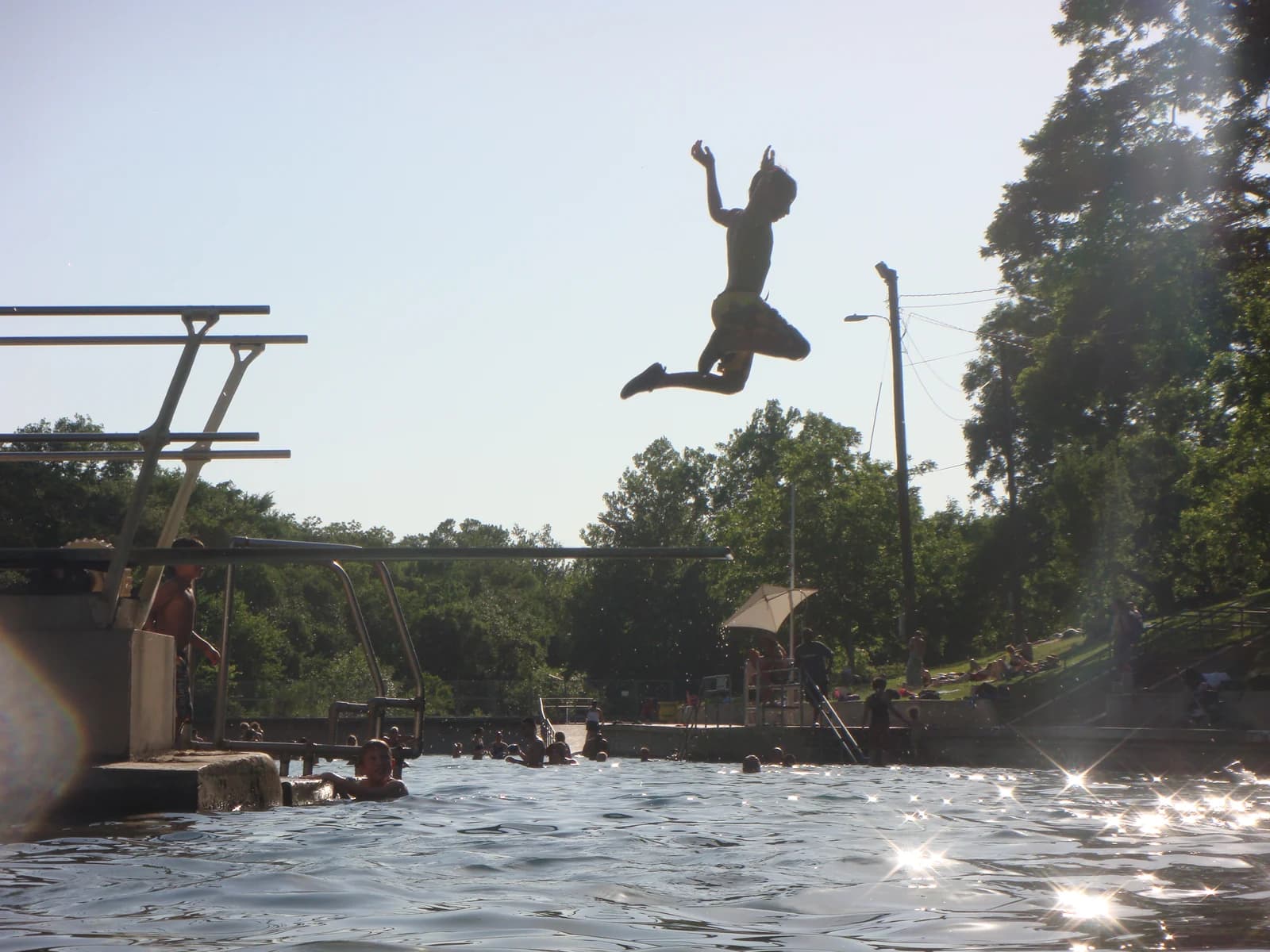A child leaping from the diving board into the spring-fed water at Barton Springs Pool in Austin