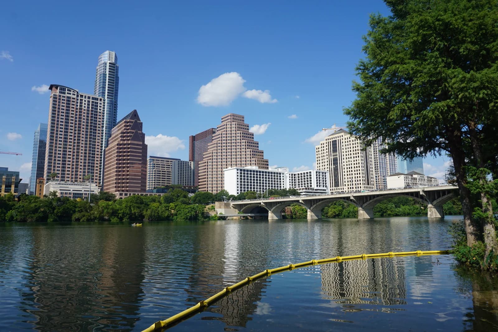 The downtown Austin skyline seen across Lady Bird Lake with the Lamar Boulevard bridge in front of it