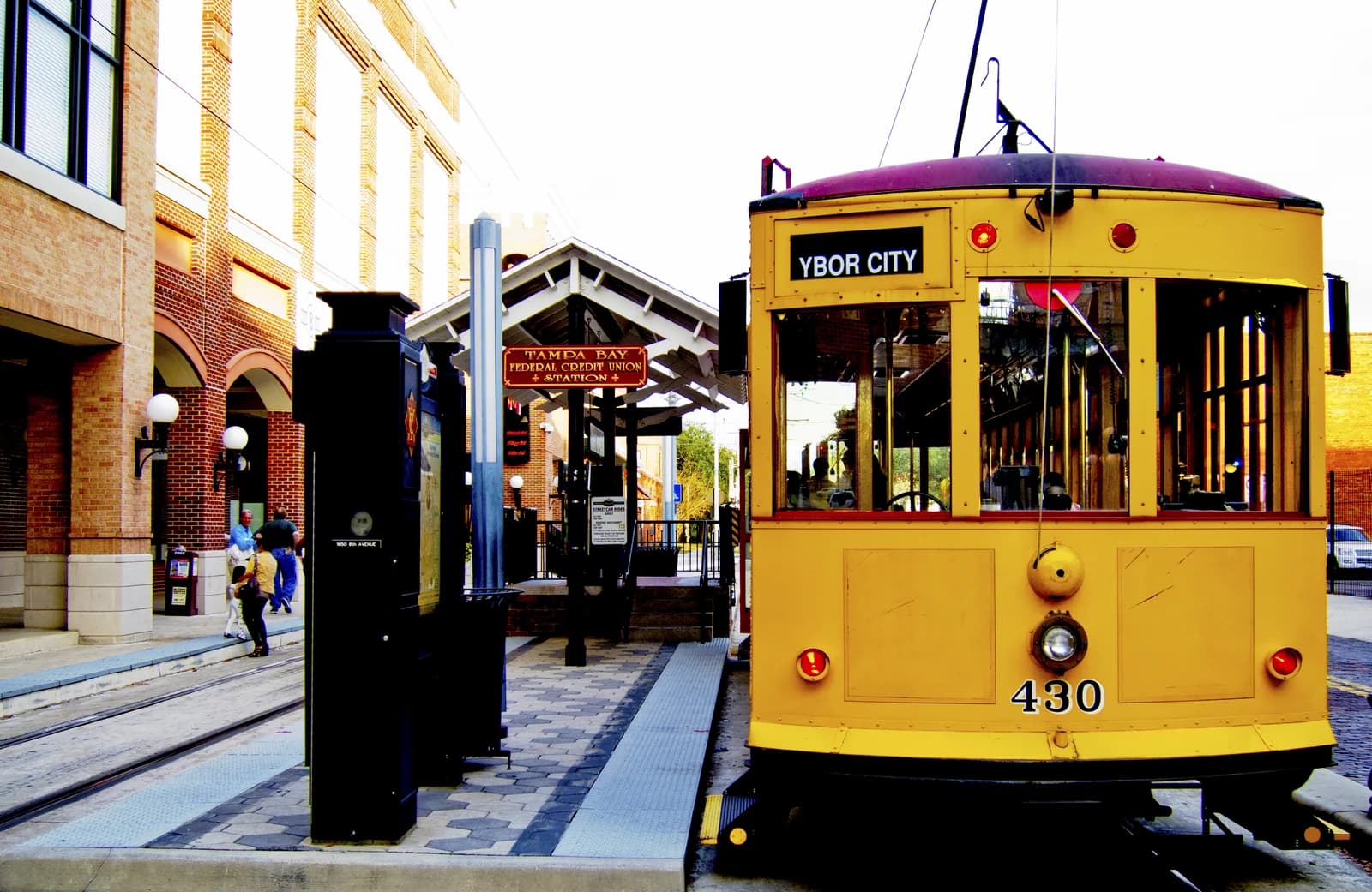 A yellow heritage streetcar marked Ybor City waiting at its station platform in Tampa