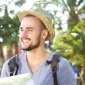 Oliver, who writes the Journey Finder city guides, holding a paper map under palm trees