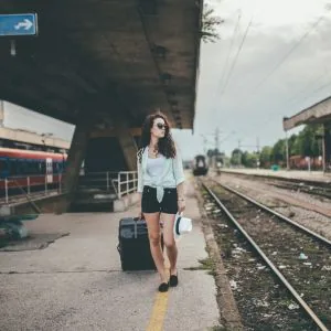 Sophie, who writes the Journey Finder transport guides, waiting on a train platform with her suitcase